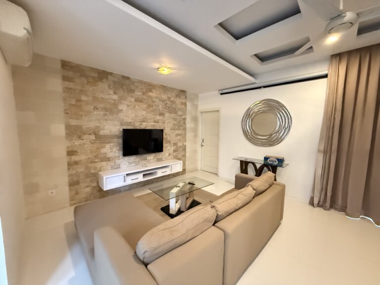 Living room with sofa, TV and stone feature wall at Panoramic Villa