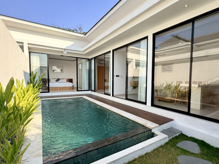 Private swimming pool and timber deck beside a villa with floor-to-ceiling glass walls