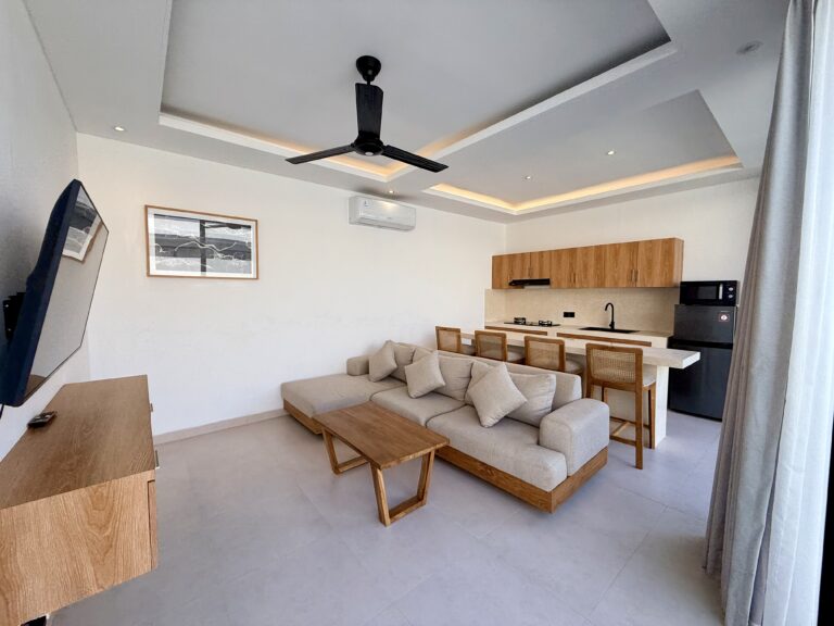 Living room with sofa, coffee table and TV, with the kitchen behind