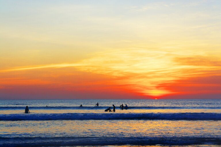 Surfers silhouetted against an orange sunset at Batu Belig Beach