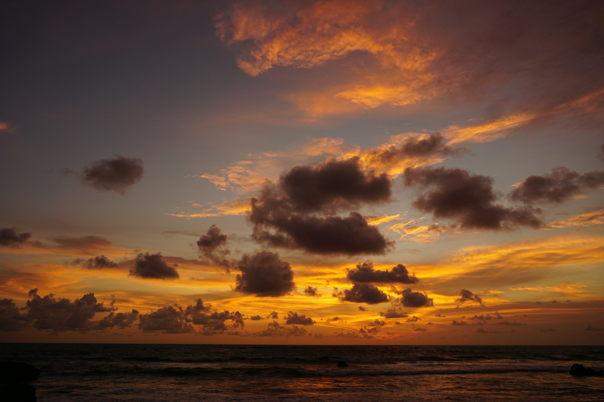 Dramatic orange sunset sky over the waves at Echo Beach, Canggu