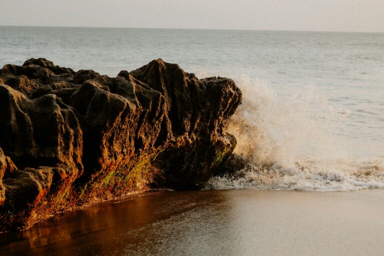 Waves breaking over dark volcanic rocks at Pererenan Beach at golden hour